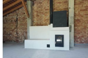 Ejemplo de estufa de inercia rocket moderna con banco acabado en cal. En lugar del bidón se puso un cubo hecho con hierro para dar la función de calor rápido