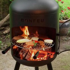 Foto de ambiente de la chimenea de exterior BonSolo Negra de Bonfeu encendida con parrilla.