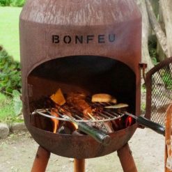Foto de ambiente de la chimenea de exterior BonSolo corten de Bonfeu encendida con parrilla.